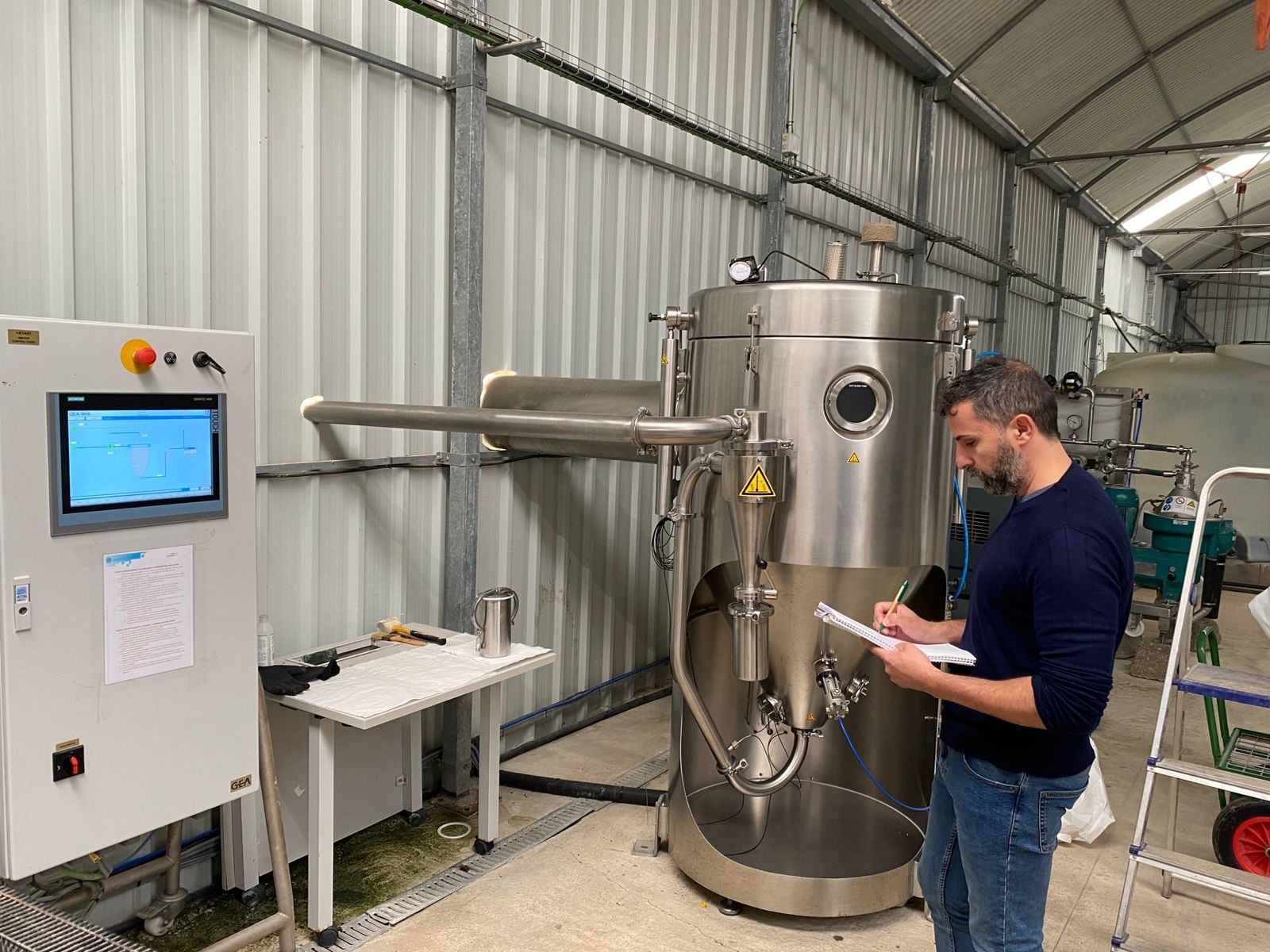 A member of the team taking notes beside the spray dryer in the plant