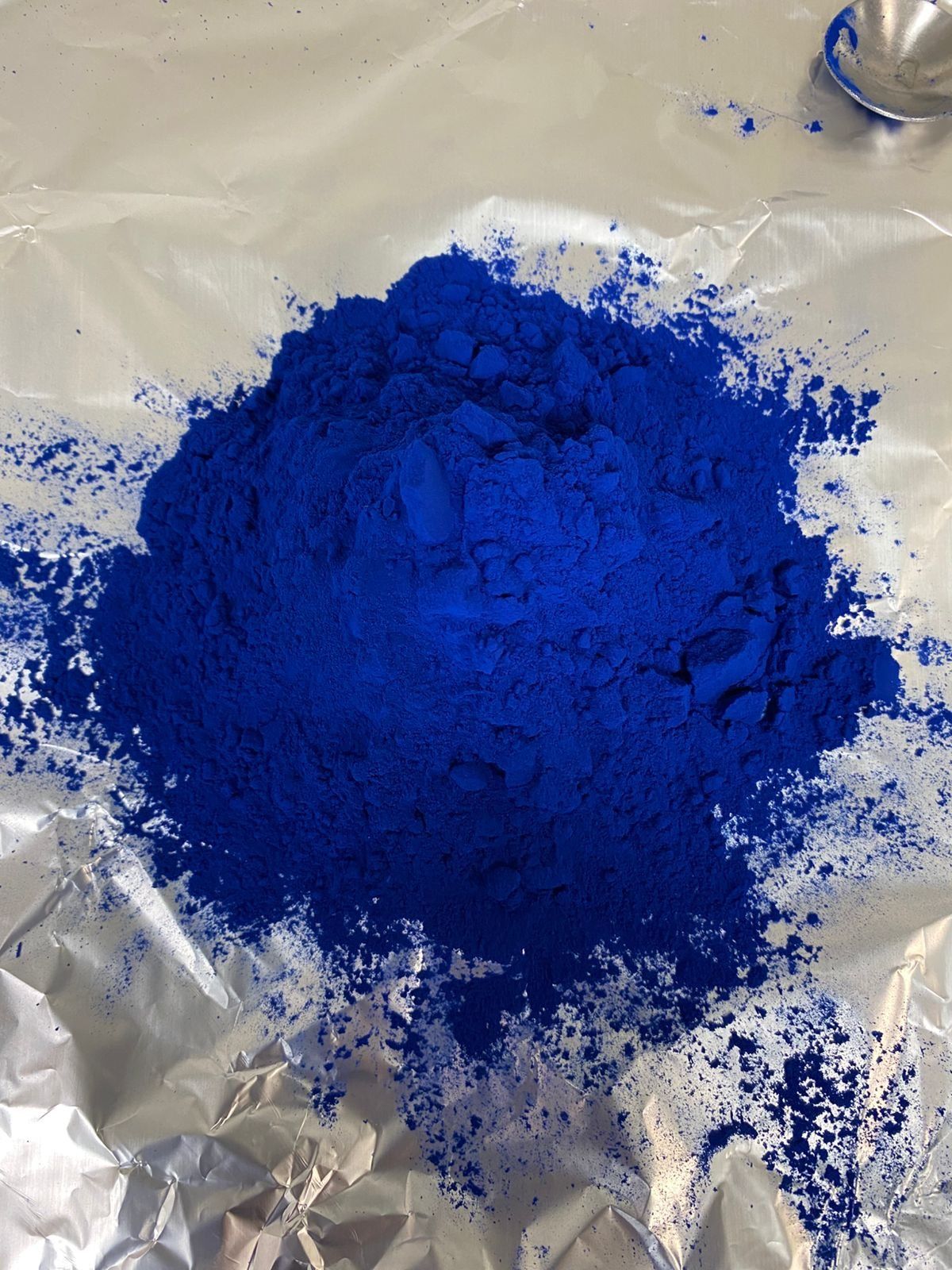 A heap of bright blue spray dried phycocyanin powder on aluminium foil